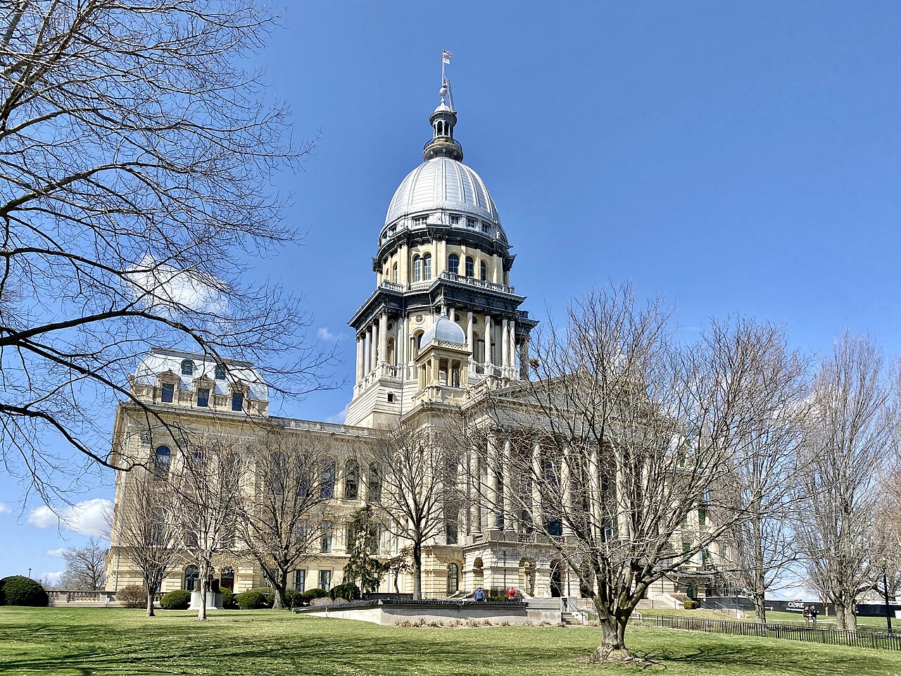 Illinois State Capitol dome and limestone facade framed by leafless trees in Springfield.