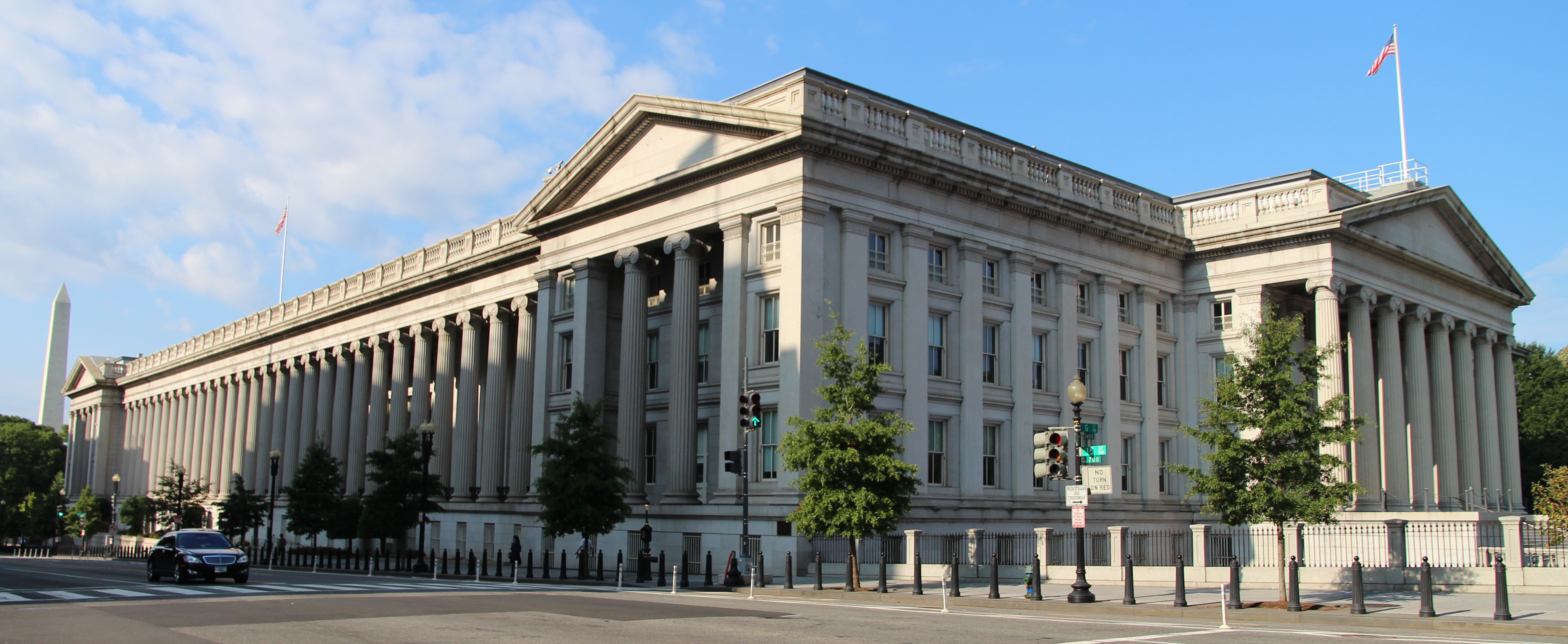 Columned facade of the United States Treasury Building in Washington, D.C., under a blue sky.